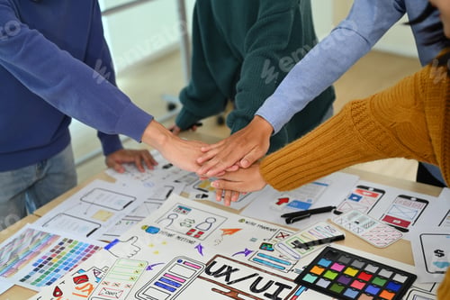 Preview: Successful creative business team stacking hands together, celebrating completion of project.