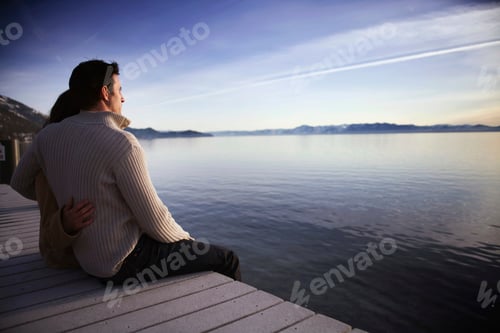 Preview: Couple sitting on pier at sunset