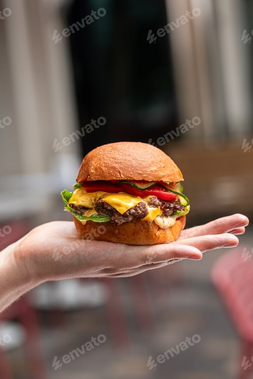 Preview: Cheeseburger on hand with cafe background