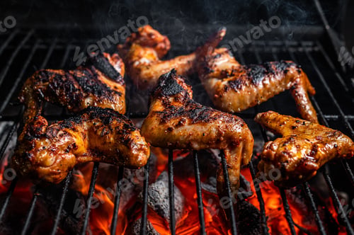 Preview: Chicken wings on barbecue, outdoor BBQ grill with fire. Top view.