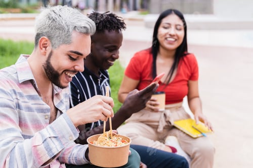 Preview: Diverse people having fun eating takeaway food outdoor - Focus on gay man wearing makeup