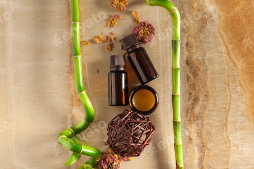 Preview: Bottles of essential oil and bamboo on wooden surface during evening light