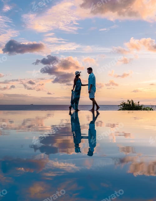 Preview: Young men and women watching sunset with reflection in the infinity pool at Saint Lucia Caribean