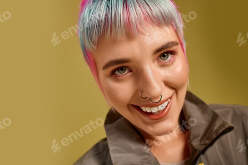 Preview: Colorful young woman with short hair poses cheerfully in a studio setting