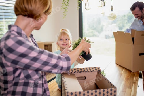 Preview: Happy family moving to their new house opening cardboard boxes together