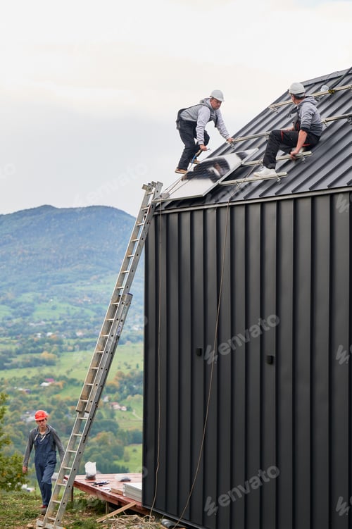 Preview: Men workers installing solar panels on roof of house.