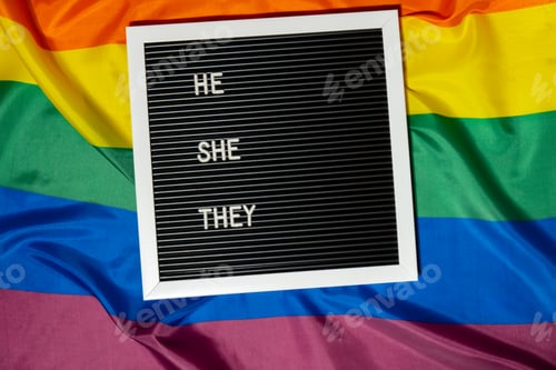 Preview: HE SHE THEY text Neo pronouns concept on Rainbow flag background gender pronouns. Non-binary people