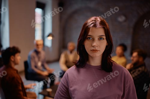 Preview: Young woman participating in mental health therapy session and looking at camera.