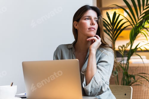 Preview: Woman surfing internet on laptop at cafe table