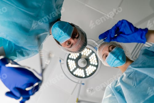 Preview: Professional surgeons in uniform bent over a patient lying on operating table