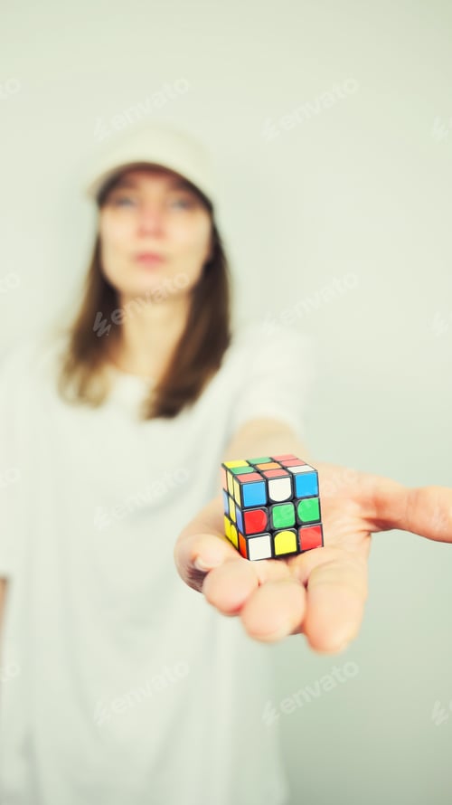 Preview: Portrait of beautiful Caucasian young female model holding Rubik's cube isolated on white background