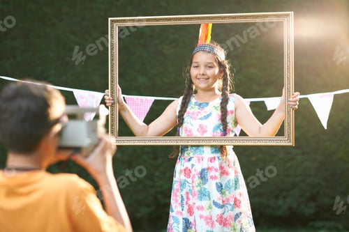 Preview: Girl looking through picture frame, having photograph taken