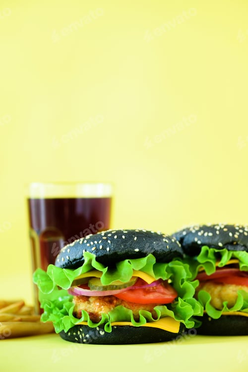 Preview: Tasty black burgers or hamburger served with french fries on yellow background. Copy space. Fast