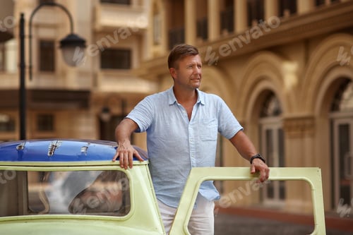 Preview: young man and green vintage car