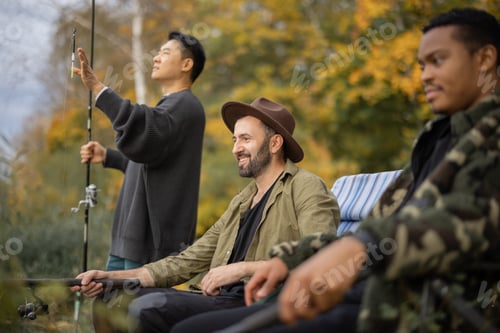 Preview: Male friends talking and fishing on lake coast