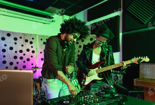 Preview: Young happy people playing music with dj mixer and guitar in house production studio