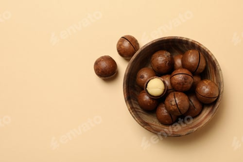 Preview: Bowl with tasty macadamia nuts on beige background