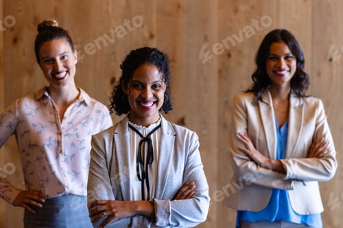 Preview: Portrait of happy diverse casual businesswomen against wooden wall in office
