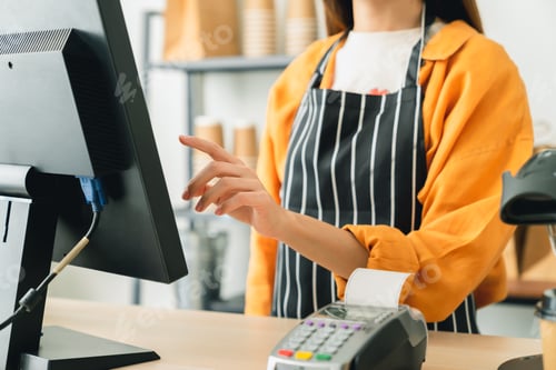 Preview: Woman cashier wears an apron and using pos terminal to input orders on coffee shop counter.
