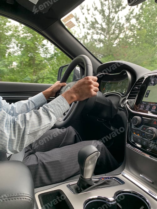 Preview: Businessman on a road trip using navigation with green trees in the window