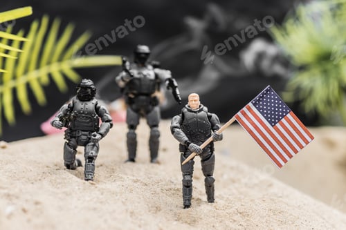 Preview: selective focus of toy soldiers with guns holding american flag on sand dune