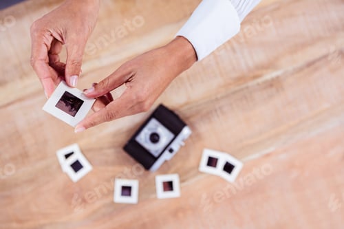 Preview: View of hands holding photo slides against wooden plank