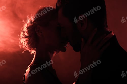 Preview: Attractive young couple almost kissing on red smoke background