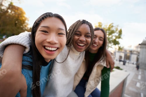 Preview: Group of three cheerful female friends looking at the camera hugging each other Happy girls outdoors