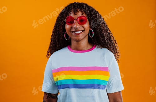Preview: Young woman showing peace sign with rainbow t-shirt and orange background