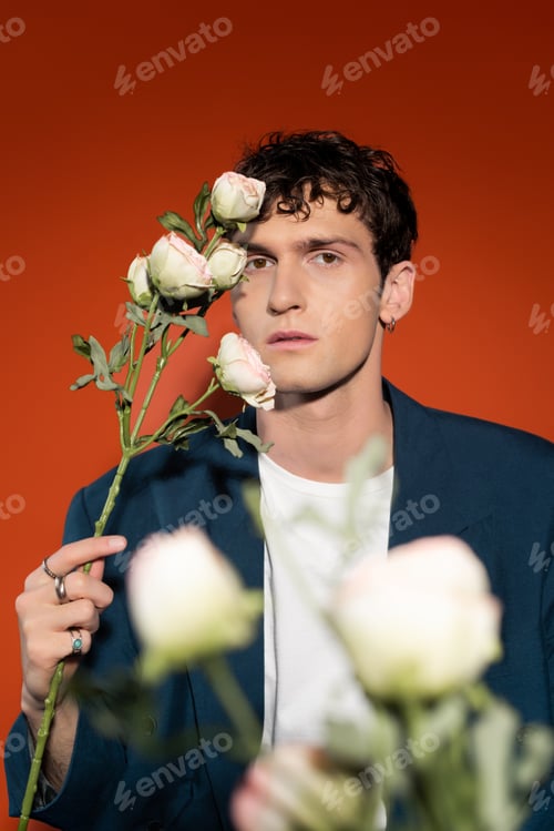 Preview: Trendy curly man holding white roses on red background