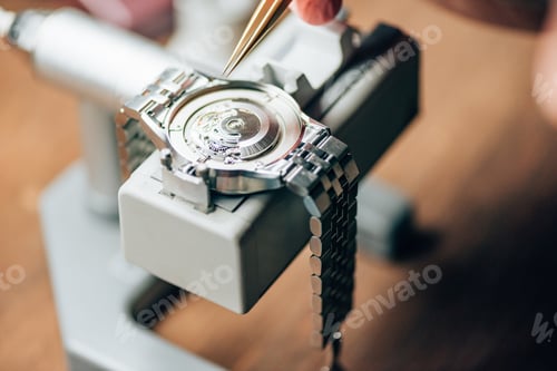 Preview: Cropped view of watchmaker working with tweezers and wristwatches on movement holder