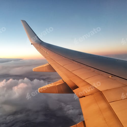 Airplane Wing Above Cloudscape at Sunrise or Sunset