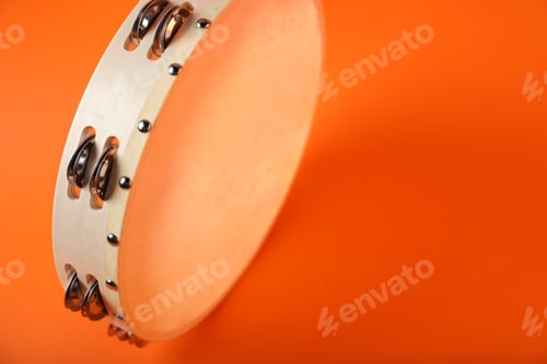 Preview: Tambourine on orange background, closeup. Space for text