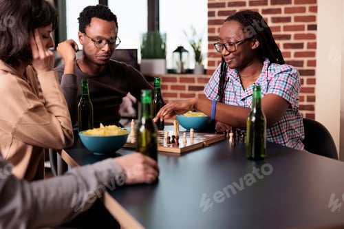 Preview: Smart people sitting at table in living room while playing chess together.
