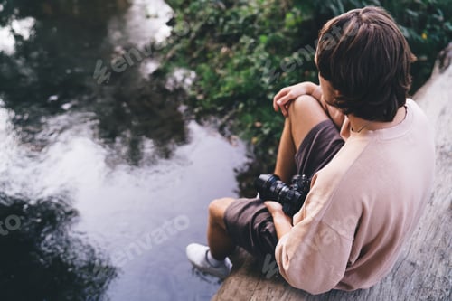 Preview: Unrecognizable boy with photo camera near river