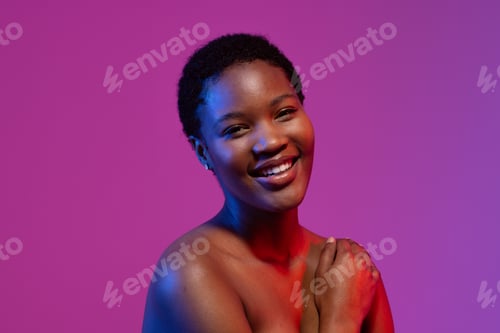 Preview: African american woman smiling with hand on shoulder in blue and red light on purple background