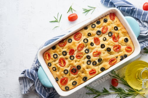 Preview: Focaccia with tomatoes, olives and rosemary in casserole, top view, copy space. Italian flat bread