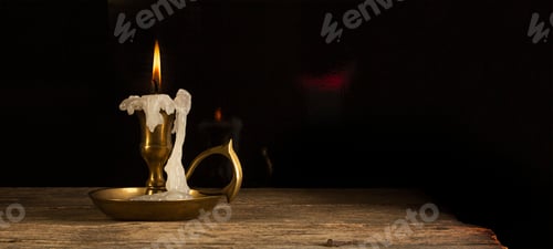 Preview: Candle in candlestick on the wooden table, vintage style, dark background.