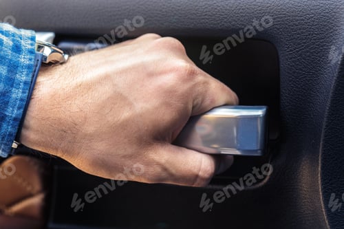 Preview: Hand reaches for car door handle in blue shirt during day