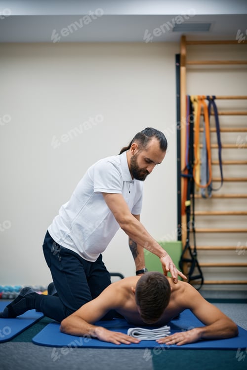 Preview: Physical therapist massaging athlete's back during rehabilitation treatment at health club.