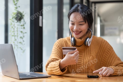 Preview: Asian woman holding credit card for online shopping and payment makes a purchase on the Internet
