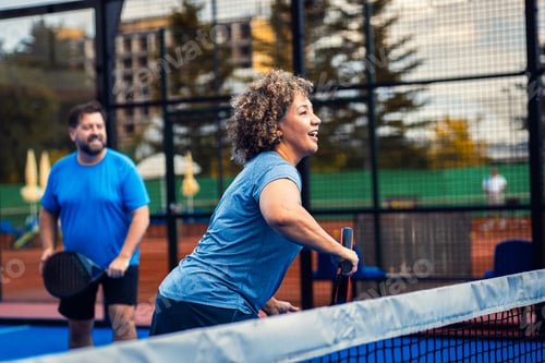 Preview: Mixed adult couple palying padel on outdoor court.