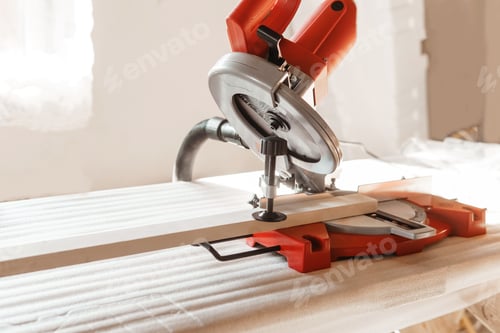 Preview: Circular saw in use cutting wooden plank inside workshop. image highlights precision