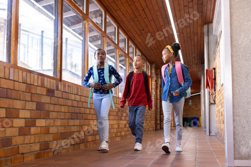 Preview: Walking in school hallway, two multiracial girls and boy with backpacks talking and smiling