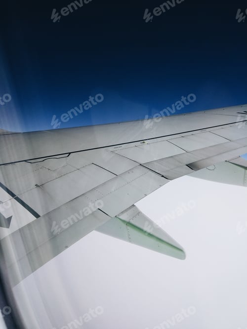 Airplane Wing Above the Clouds in Blue Sky
