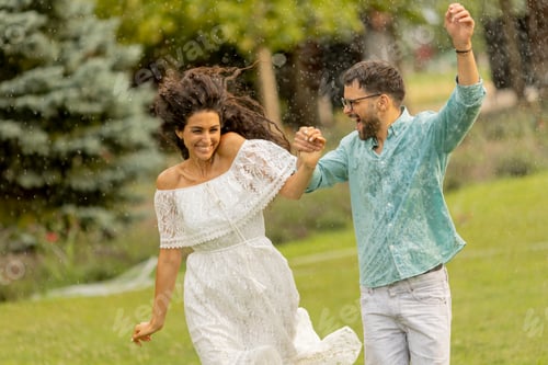 Preview: Joyful young couple caught by the summer rain in the park