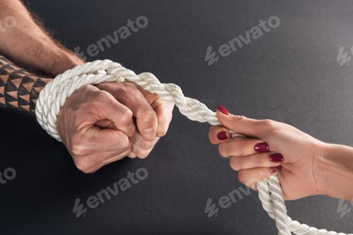 Preview: cropped view of woman holding rope on male hands on black background