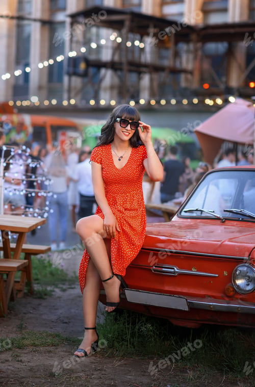 Preview: beautiful caucasian girl in a red dress and glasses on a walk in the city