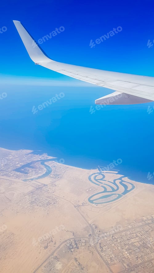 Preview: View from the window of plane on blue sky and earth with landscape of desert, sea and canals in