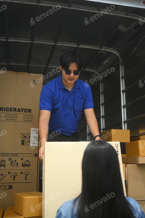 Preview: Male courier standing inside a truck, preparing to hand over package to a customer
